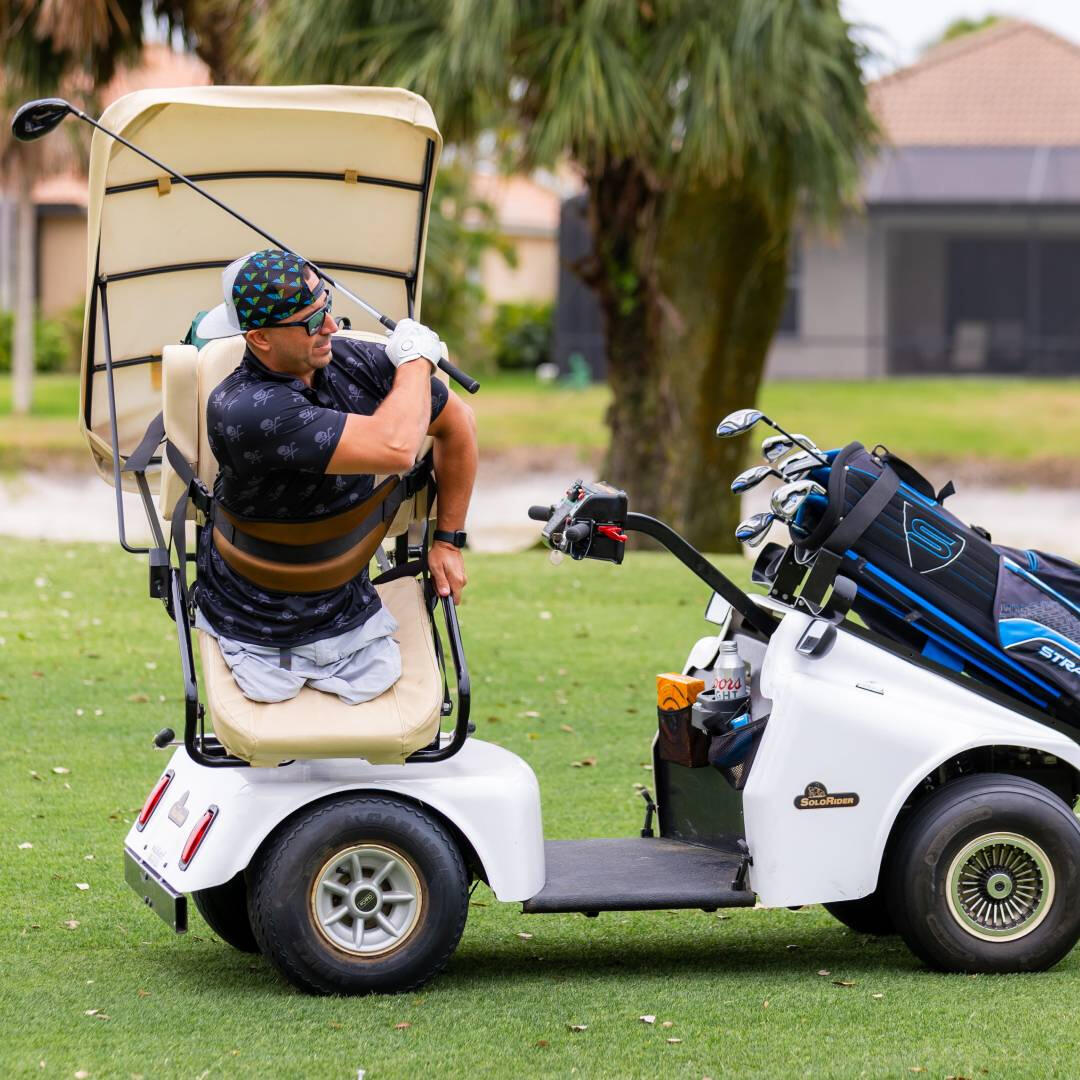 A handicapped man playing golf in a specialized golf cart