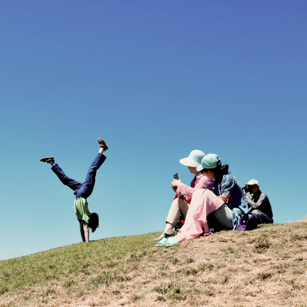 An Asian family on the grass doing acrobatics at Gas Works Park in Seattle, Washington